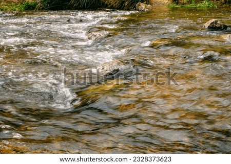 Rapid and powerful water flow between large rocks, close-up. Boulders in cold mountain river. Natural backgrounds