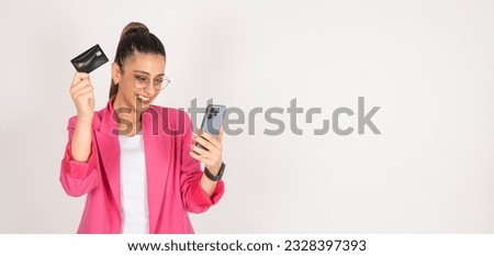 Using smartphone and credit card, portrait of young brown haired beautiful woman using smartphone and credit card. Businesswoman wearing pink jacket. Shopping online in application. Excited girl. 