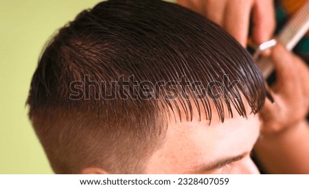 hairstylist with scissors and a comb create a straight fringe for a young man Royalty-Free Stock Photo #2328407059