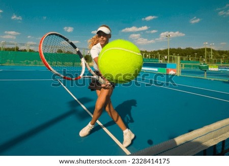 A girl plays tennis on a court with a hard blue surface on a summer sunny day. focus on tennis ball  Royalty-Free Stock Photo #2328414175