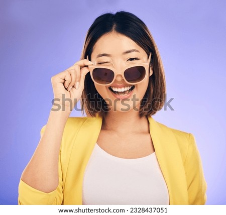 Happy, portrait of asian woman wink with glasses in studio, purple background and fashion. Face, female model and blink emoji with sunglasses for secret, fun personality and gen z girl in good mood Royalty-Free Stock Photo #2328437051
