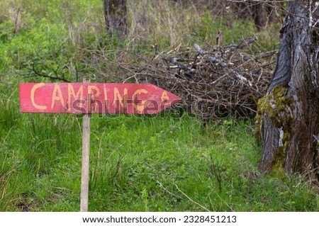 Rustic handcrafted camping sign on wooden plank arrow in nature. Authentic directional signpost with text for camping area in forest.