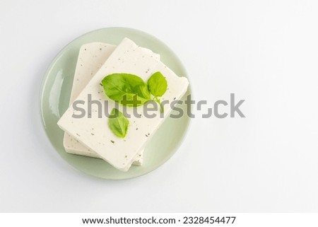 Top view of  tofu, paneer or soy cheese with fresh basil leaves in a green plate isolated with copy space Royalty-Free Stock Photo #2328454477