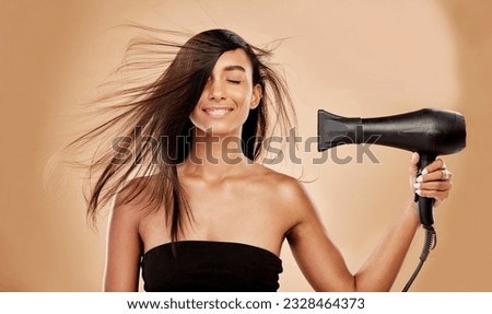 Hair, dryer and smile of woman in studio for beauty, grooming and heat equipment on background. Indian female model, haircare and tools with wind for hairstyle, salon appliance or aesthetic treatment Royalty-Free Stock Photo #2328464373
