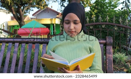 Relaxed muslim woman enjoying weekend at park, sitting on bench and reading book, empty space