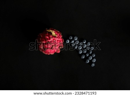 Minimalist still life of blueberries and red dragon fruit on a black background