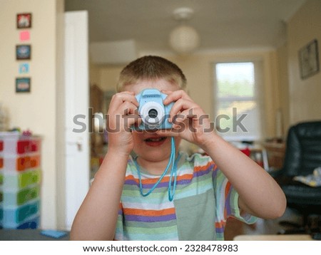 Young four year old child taking photos with a small plastic camera