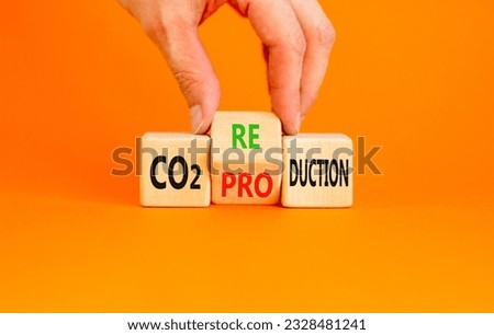 CO2 production or reduction symbol. Concept word CO2 production reductionon a wooden block on a beautiful orange background. Businessman hand. Business ecological and CO2 changes concept. Copy space.