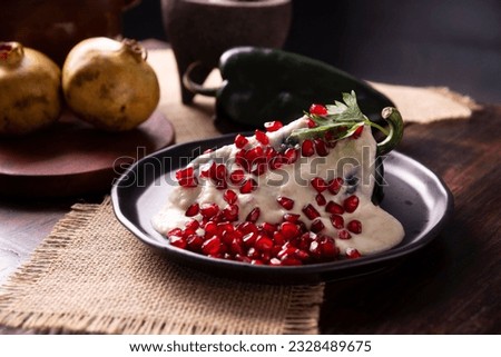Chiles en Nogada, Typical dish from Mexico. Prepared with poblano chili stuffed with meat and fruits and covered with a walnut sauce. Named as the quintessential Mexican dish for national holidays. Royalty-Free Stock Photo #2328489675