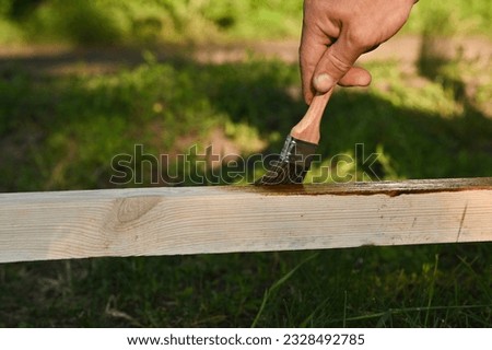 Painting protective varnish on wooden wooden bar at outdoors.