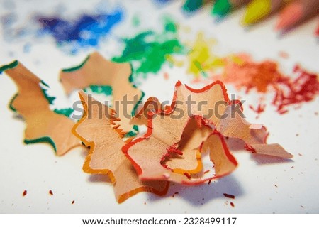 Shavings from red, orange and green pencils lie on white paper close-up. Drawing, school, classes, art. Stationery, coloring pages, sharpeners, pencil cases. Art therapy, psychology, office.