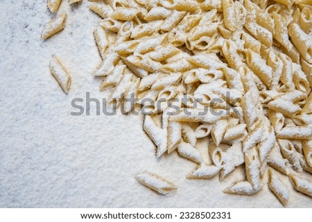 Penettine pasta in the flour. ingridienti of typical Italian cuisine. Penettine raw pasta  Royalty-Free Stock Photo #2328502331