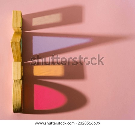 Colorful geometric shapes and their colored shadows on pastel pink background. Minimal optical concept. Abstract geometric background. Flat lay, top of view. Copy space.