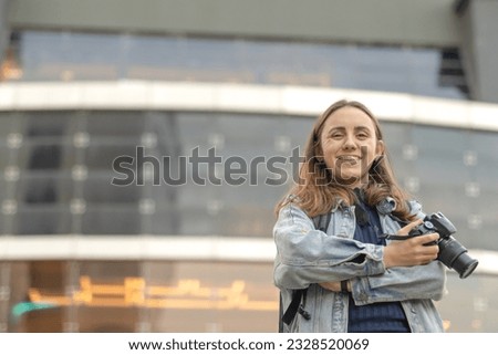Woman photographer smiling with mirrored building in blurred background. Photography day concept. Copy space