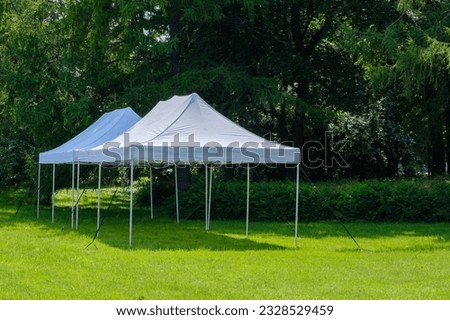 White tents for guests in the park. Party in nature Royalty-Free Stock Photo #2328529459