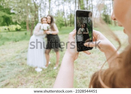 Girls at a wedding take photos on a smartphone. Wedding walk in the forest