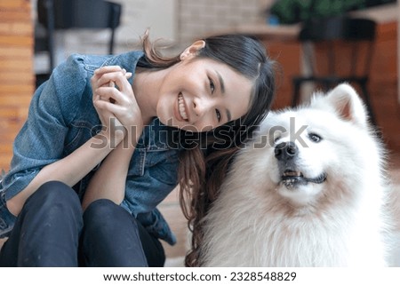 Beautiful asian woman posing with lovely friendly samoyed breed of medium-sized herding dogs with thick, white, double-layer coats at home, companion animal, family, friendship, life balance concept.