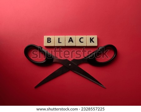 Scissors and toys letters with the word BLACK on a red background