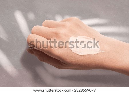 Cosmetic cc cream taster swatch smudge on woman hand on gray stone background Royalty-Free Stock Photo #2328559079