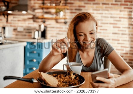 Young woman using a smart phone while having breakfast in the morning