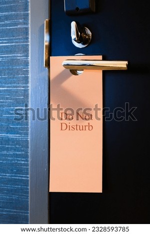 Classic American hotel door sign. Do Not Disturb. Sign hangs on a sleek contemporary modern door knob in a luxury hotel environment. Stay Away. Leave Me Alone. High quality photo