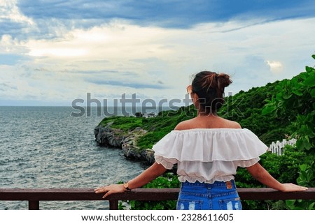 Portrait of a young woman wearing sunglasses Standing watching the sun about to set by the sea shore