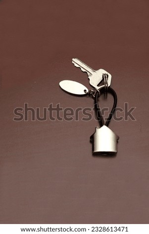 Silver key ring in the shape of a house with the key to a new home recently bought in real estate to create a home