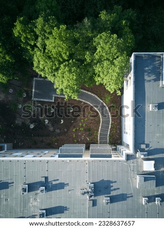 Aerial top down view of single apartment block during summer with walking paths. Drone photo.