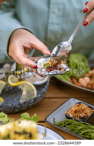 motion picture, she eating a oyster with spicy dripping asian style, many delicious food on wooden table