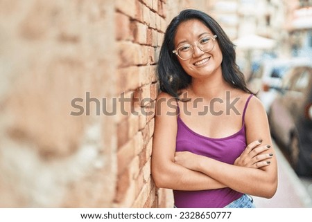 Young chinese woman standing with arms crossed gesture at street