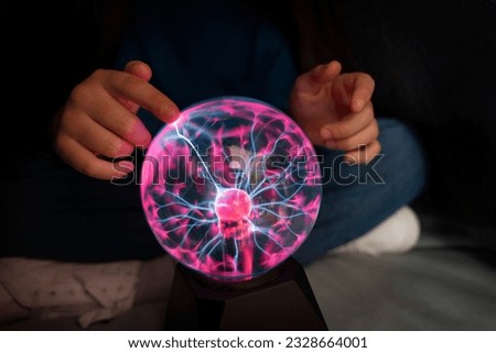 plasma ball. Hands holding plasma light ball. Plasma ball light ray science. Finger touching Plasma ball with smooth magenta blue flames. Electromagnetic Fields in a glass globe. Royalty-Free Stock Photo #2328664001