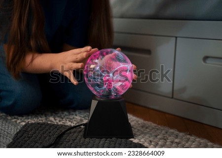 plasma ball. Hands holding plasma light ball. Plasma ball light ray science. Finger touching Plasma ball with smooth magenta blue flames. Electromagnetic Fields in a glass globe. Royalty-Free Stock Photo #2328664009