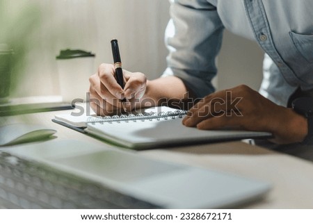man hands with pen writing on notebook in the office.learning, education and work.writes goals, plans, make to do and wish list on desk. Royalty-Free Stock Photo #2328672171