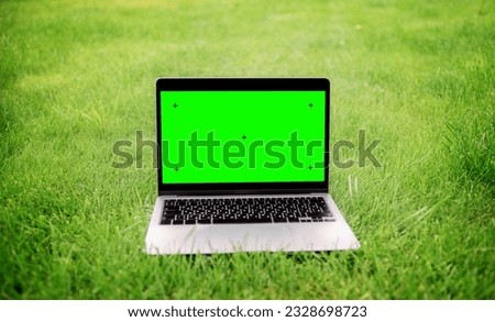 Notebook on the green grass of the campus lawn. Green screen laptop