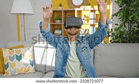 Young caucasian man playing video game using virtual reality glasses at home