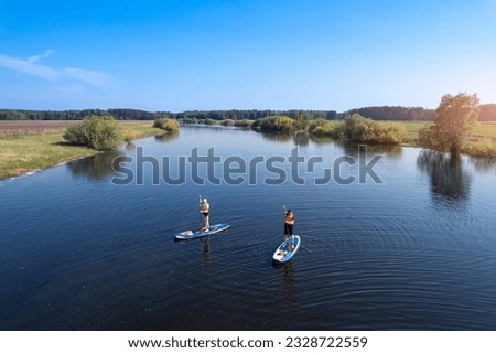 Summer active sport on river, happy friends man and woman floats on supboard.