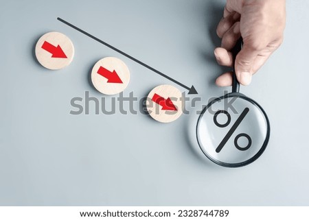 Magnifier focus to Percentage decreasing arrows cost down concept. Financial interest rates decline and profit down of investing.