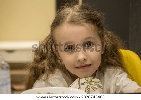 A little girl with brown eyes looks thoughtfully. The concept of childhood, peace and tranquility in a child's gaze