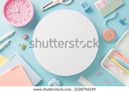 Stationery for successful education presented in this top-view photo of notepads, pens and clips, pencil case and other pastel colored items on blue isolated background with empty circle for copyspace