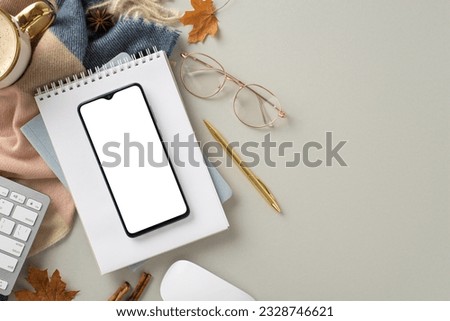Experience coziness of freelance work in autumn with this top view picture featuring phone on notepad with gilded pen and glasses, hot cacao with cozy scarf on beige isolated background with copyspace