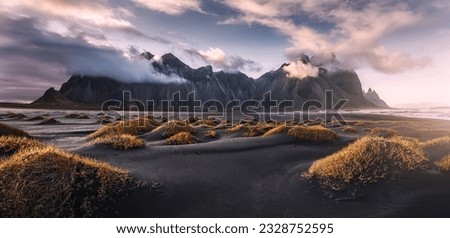 Stunning moody dramatic landscape image with cloudy mountain in Iceland during sunset. Impressive Colorful Seascape of Iceland. Wonderful picturesque Scene  near Stokksnes cape and Vestrahorn Mountain Royalty-Free Stock Photo #2328752595