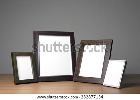 four empty(blank) wood photo frames(walnut, steel) on the wood table(desk) at the studio.