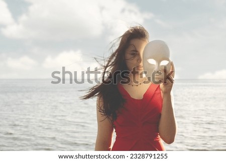 woman hiding half face behind a mask, abstract concept Royalty-Free Stock Photo #2328791255