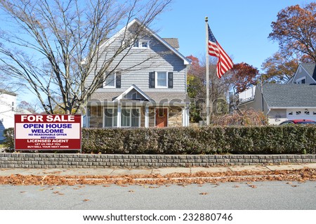 American flag pole Real Estate for sale open house welcome suburban gable style home hedges autumn day residential neighborhood blue sky USA