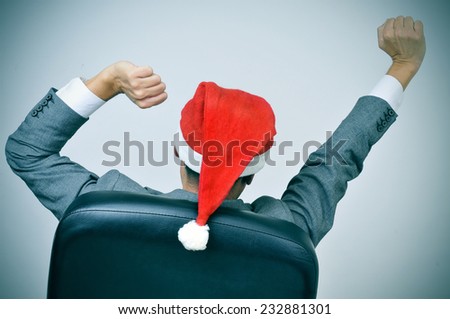 a man in suit with a santa hat stretching his arms in his office chair
