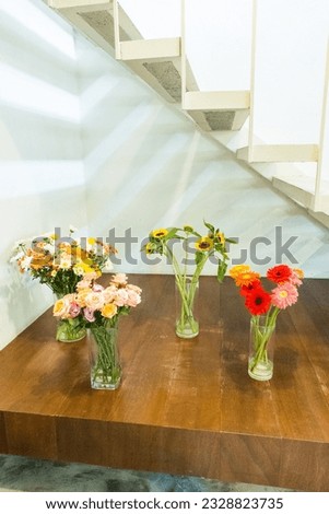 Sunflowers and rose in glass vase on wooden table.