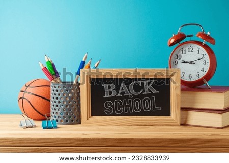 Back to school background with pencils, basketball ball, books and chalkboard on wooden table over blue background