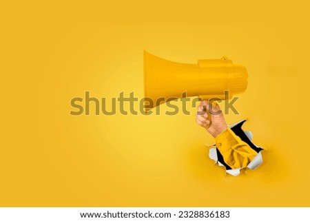 Loudhailer, hand holding megaphone breakthrough paper hole. Announcement, advertising, public hearing concept. Mockup design with loudspeaker, Torn background with blank empty space for copy space. Royalty-Free Stock Photo #2328836183