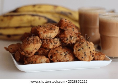 Bite sized plantain fritters. Ripe plantain disk dipped in a batter of whole wheat flour and sesame seeds and deep fried. Commonly known as ethakka appam. Shot along with plantain and glass of tea Royalty-Free Stock Photo #2328852215