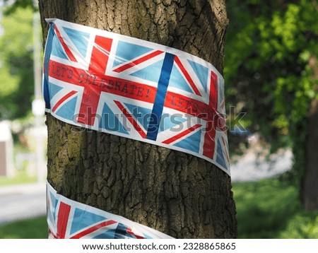 Union Jack flag with LETS CELEBRATE written across it wrapped around a tree trunk on the day of King Charles’s Coronation